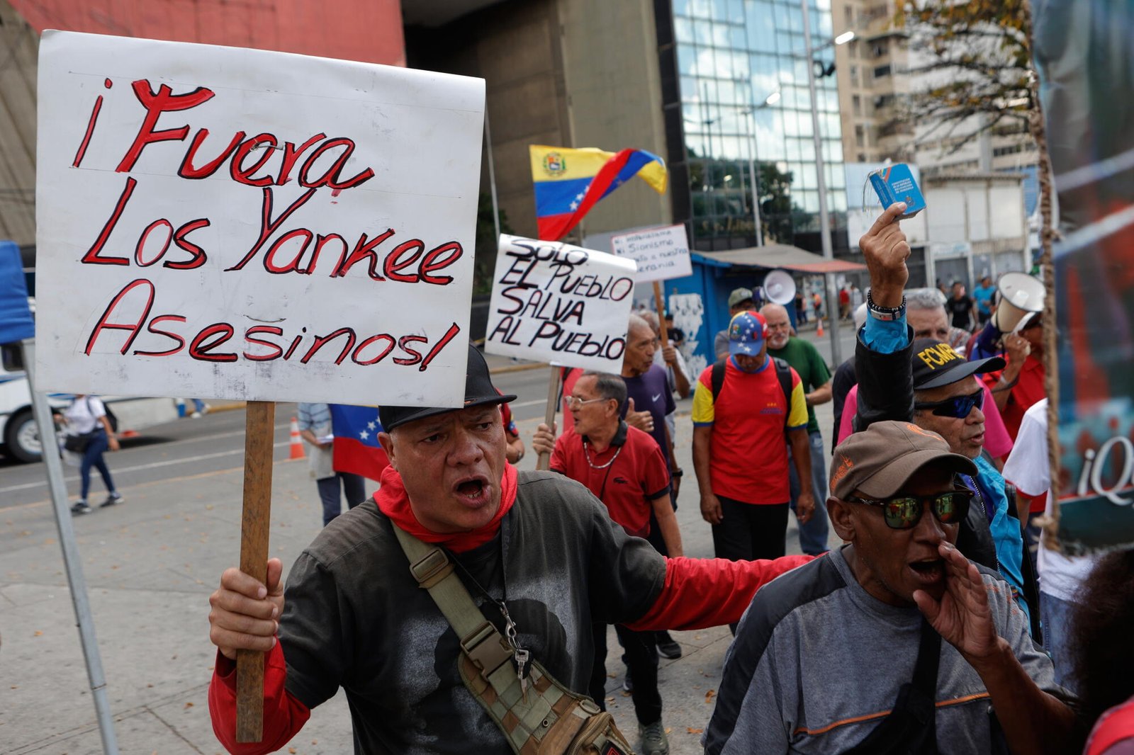 Un hombre sostiene un cartel con un mensaje en español. "Fuera Yankees, asesinos." durante la protesta