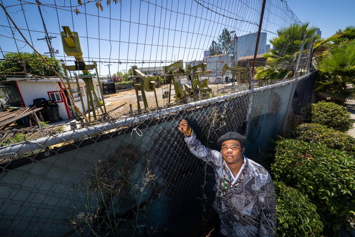 El activista climático Sim Bilal junto a una bomba en un campo petrolero en Los Ángeles en 2024.