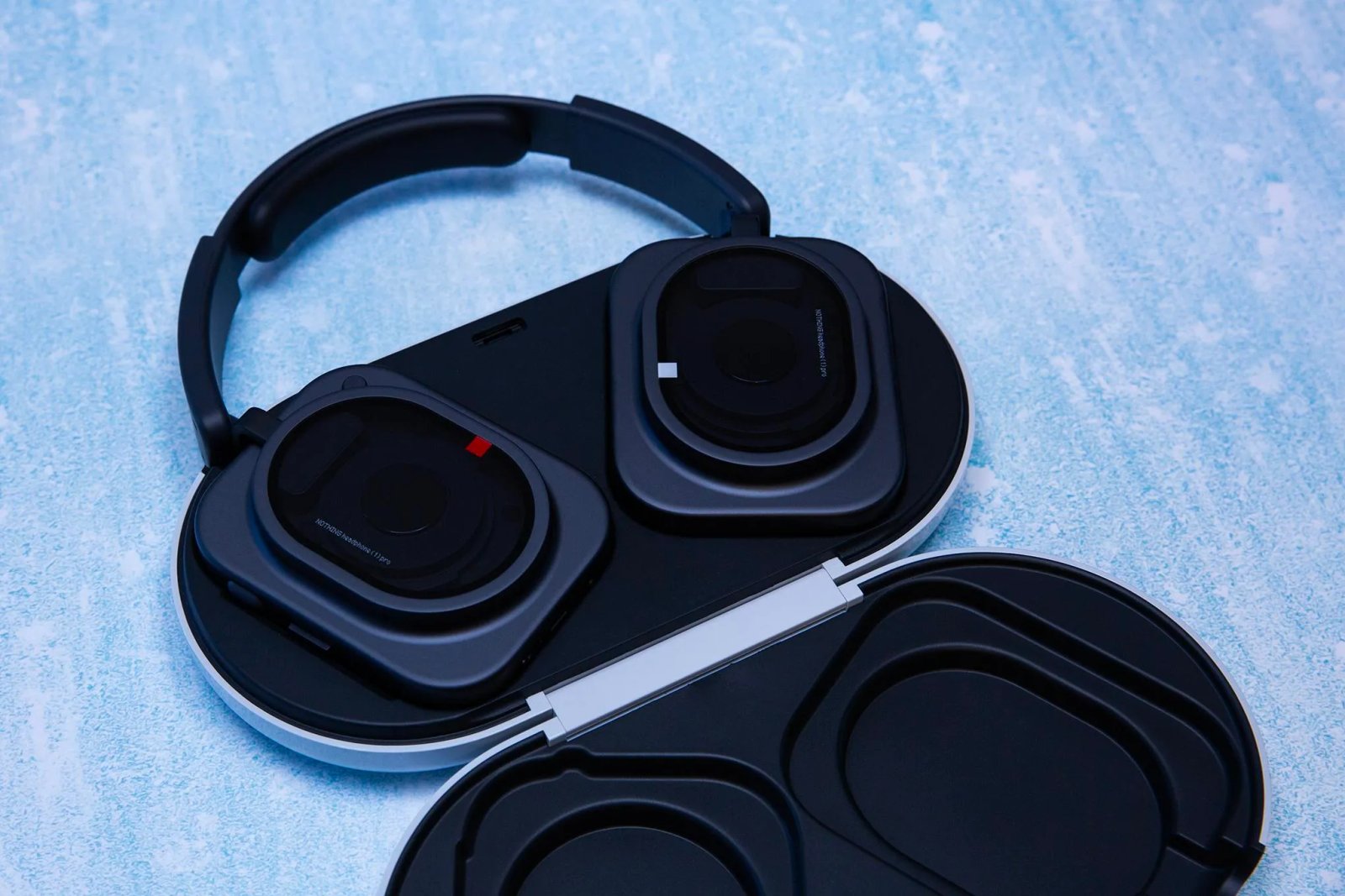 Los auriculares Black Nothing Pro 1 se colocan en una caja abierta sobre un fondo azul.