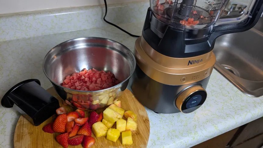 Ninja - CrushBoss - Procesador de alimentos - Tazón junto a sandía cortada en cubitos y fruta fresca en una tabla para cortar