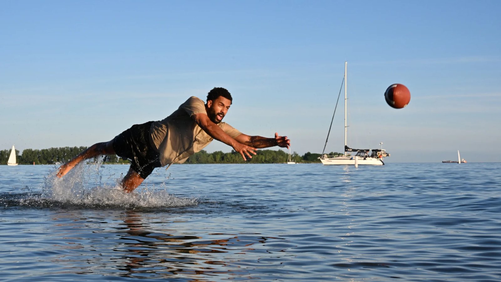 Un hombre se para en el agua y se lanza para atrapar la pelota.