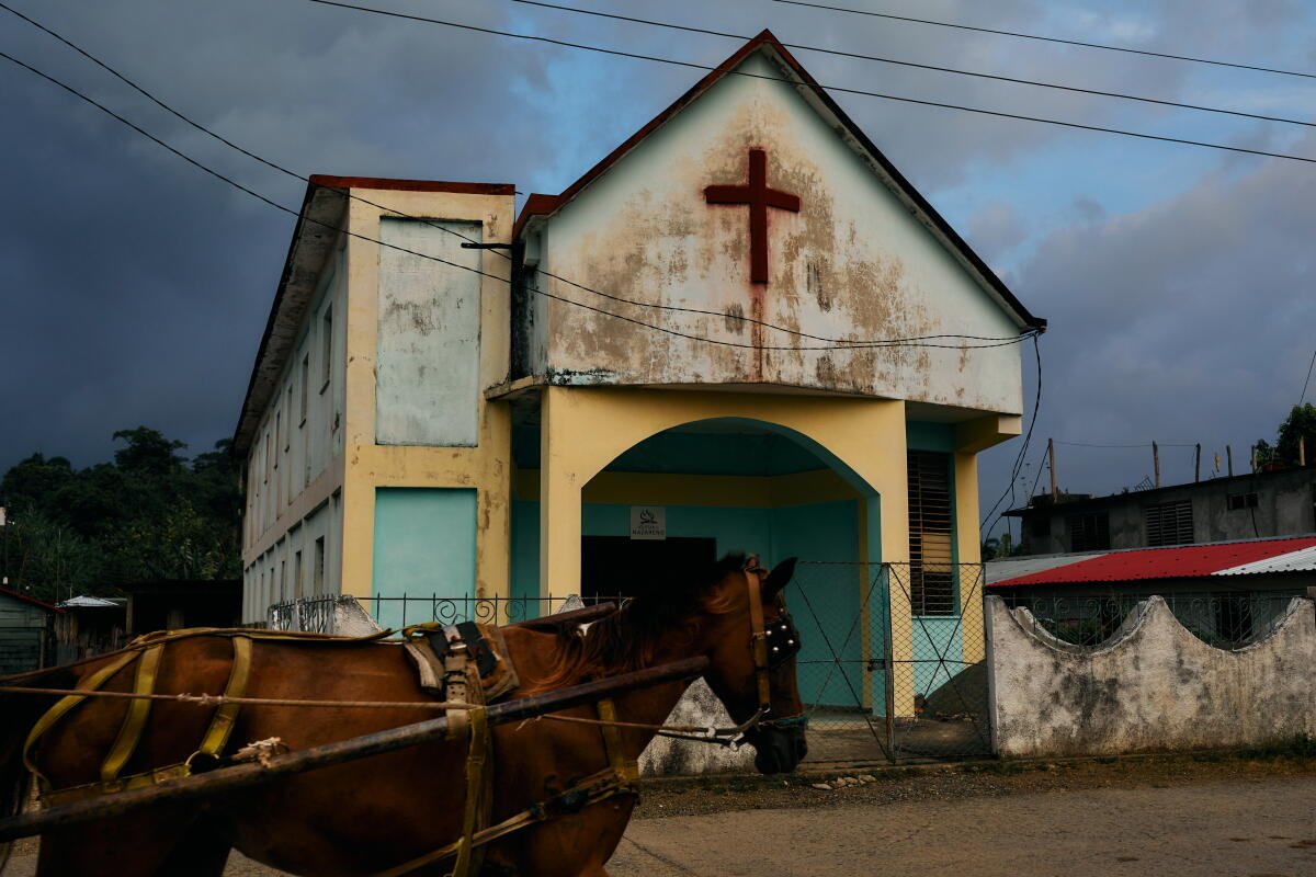 Un carruaje tirado por caballos pasa frente a una iglesia en Baracoa. En el extremo oriental de Cuba