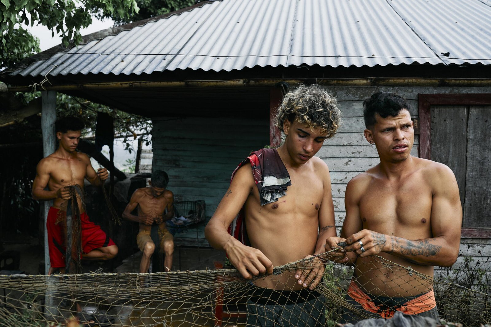 Cuatro hombres reparan redes de pesca para pescar alimentos durante todo el día en Baracoa.