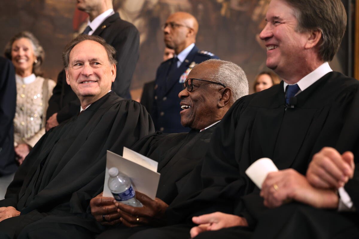 Los jueces asociados de la Corte Suprema Samuel Alito, Clarence Thomas y Brett Kavanaugh se ríen.