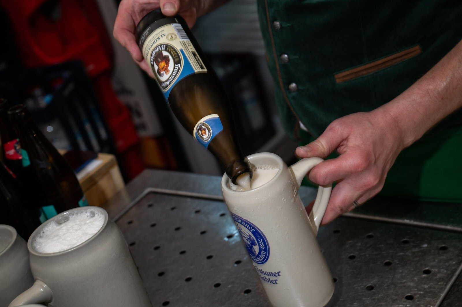 El camarero sirve Weissbier sin alcohol de la botella en un vaso de gres.