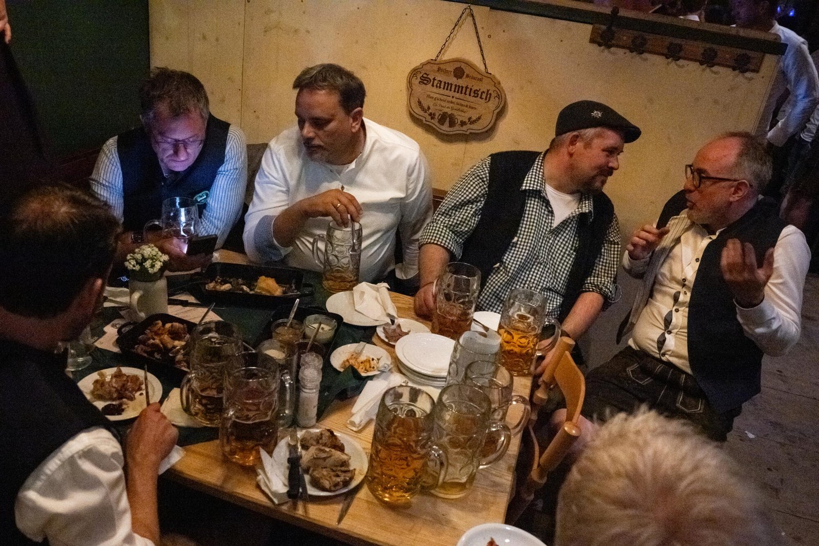 Los hombres se sientan alrededor de una mesa en la mesa habitual del Pschorr Braurosl Festzelt en el Oktoberfest.