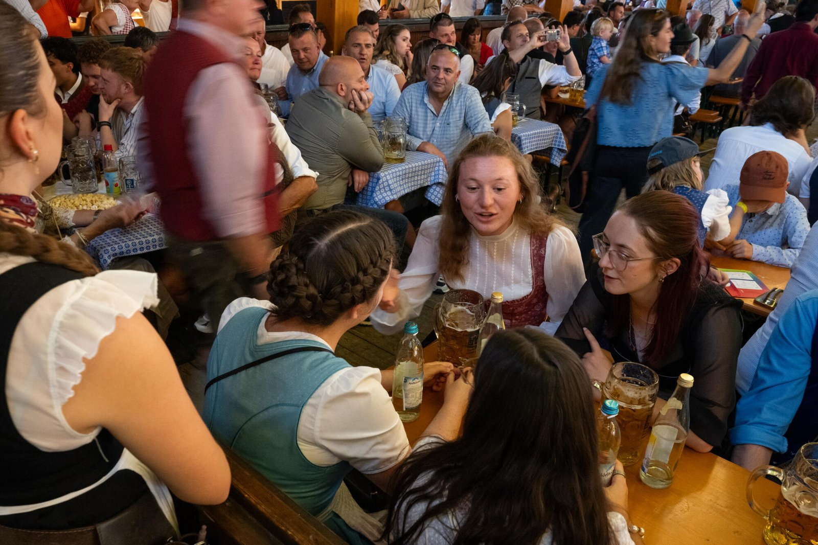 Amigos charlando en la mesa con vasos de cerveza y botellas de agua de varios litros.