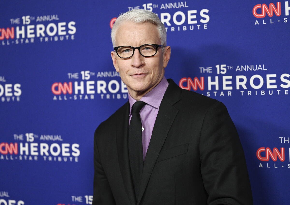 Un hombre de pelo blanco con gafas y traje.