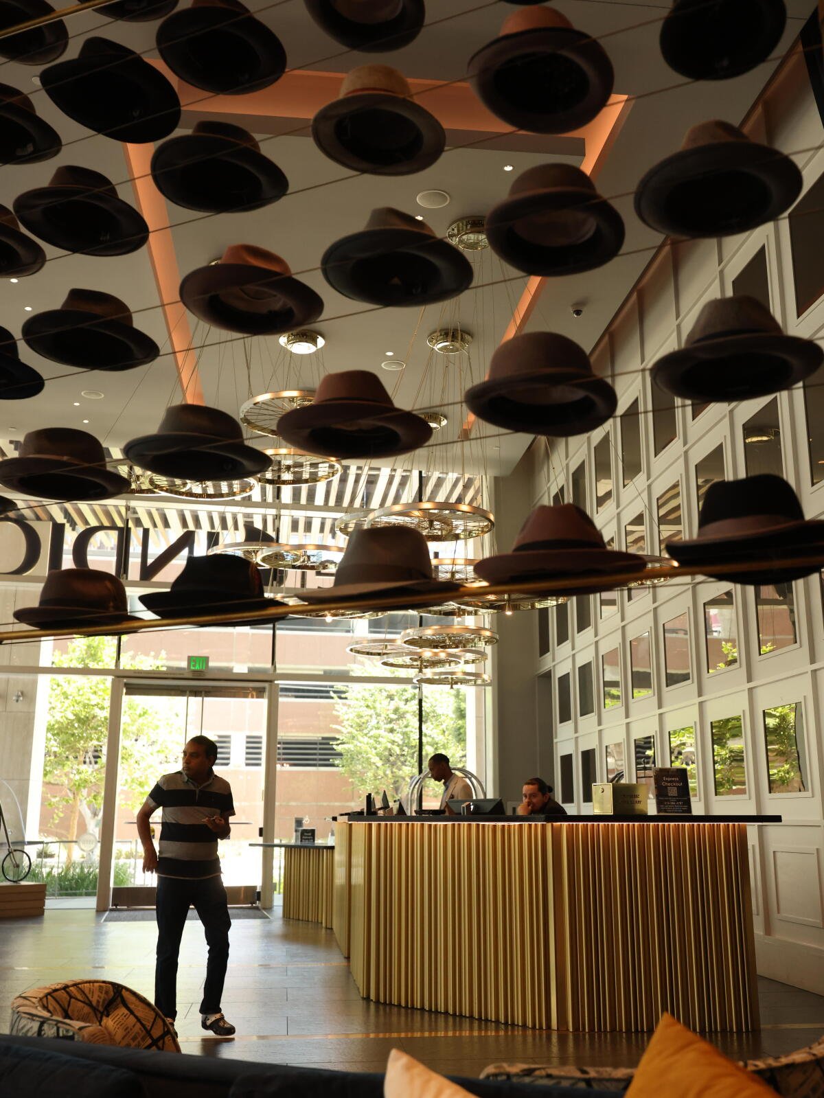 Los visitantes caminan bajo los sombreros expuestos en el vestíbulo del hotel.