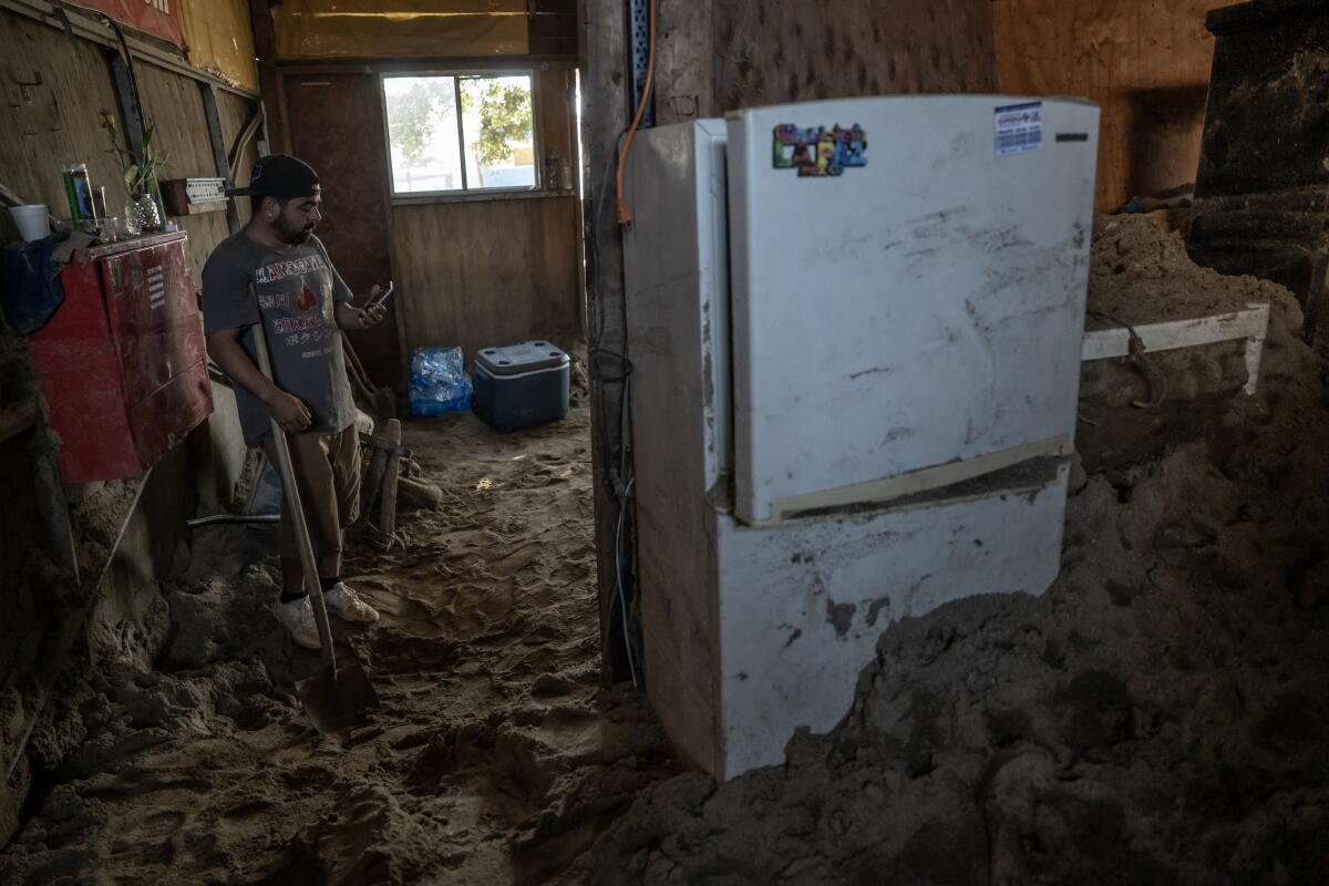 Vecinos de la comunidad Maneadero limpian lodo y escombros de viviendas inundadas.