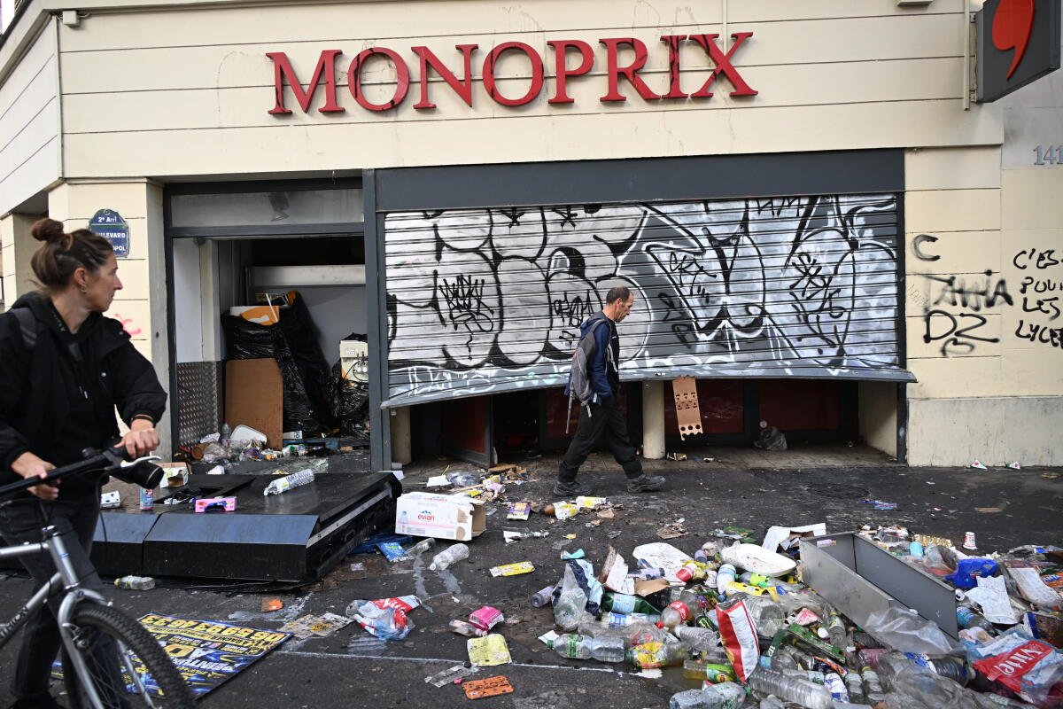 La gente pasaba frente a tiendas saqueadas con graffitis y escombros en la acera.