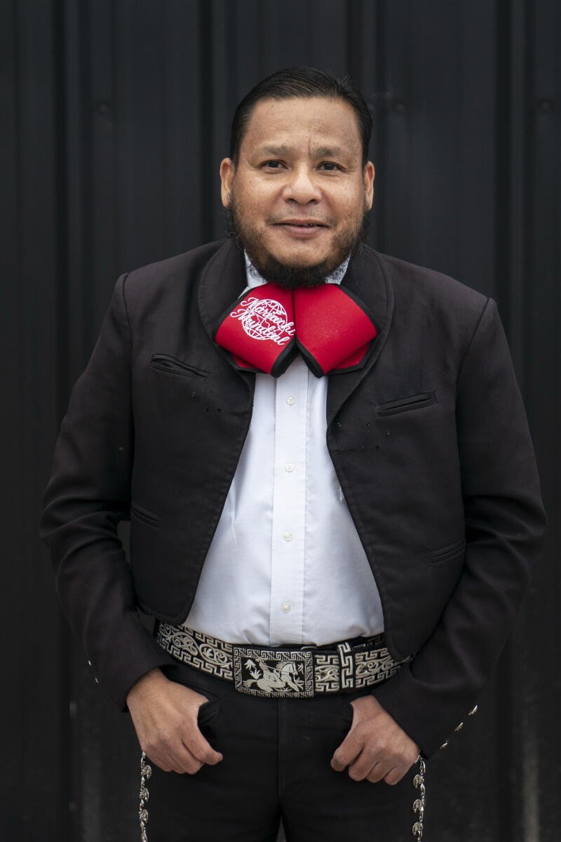 Hombre disfrazado de mariachi con lazo rojo