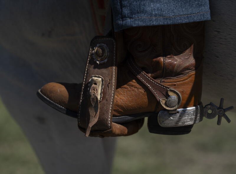 Foto de una bota marrón con espuelas en el estribo.