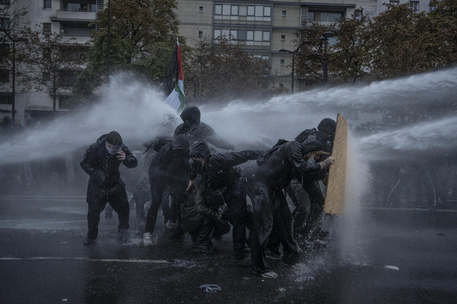Un grupo de manifestantes se defiende de un cañón de agua.