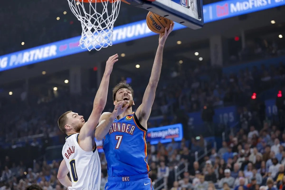 22 de octubre de 2026; Ciudad de Oklahoma, Oklahoma, Estados Unidos; El centro de Oklahoma City Thunder, Chet Holmgren (7), conduce una canasta pasando por el guardia de Denver Nuggets, Christian Brown (0) durante el primer cuarto en el Paycom Center. Crédito obligatorio: Alonzo Adams-Imagn Images