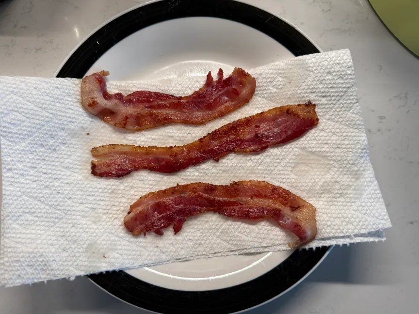 3 tiras de tocino cocido colocadas sobre toallas de papel